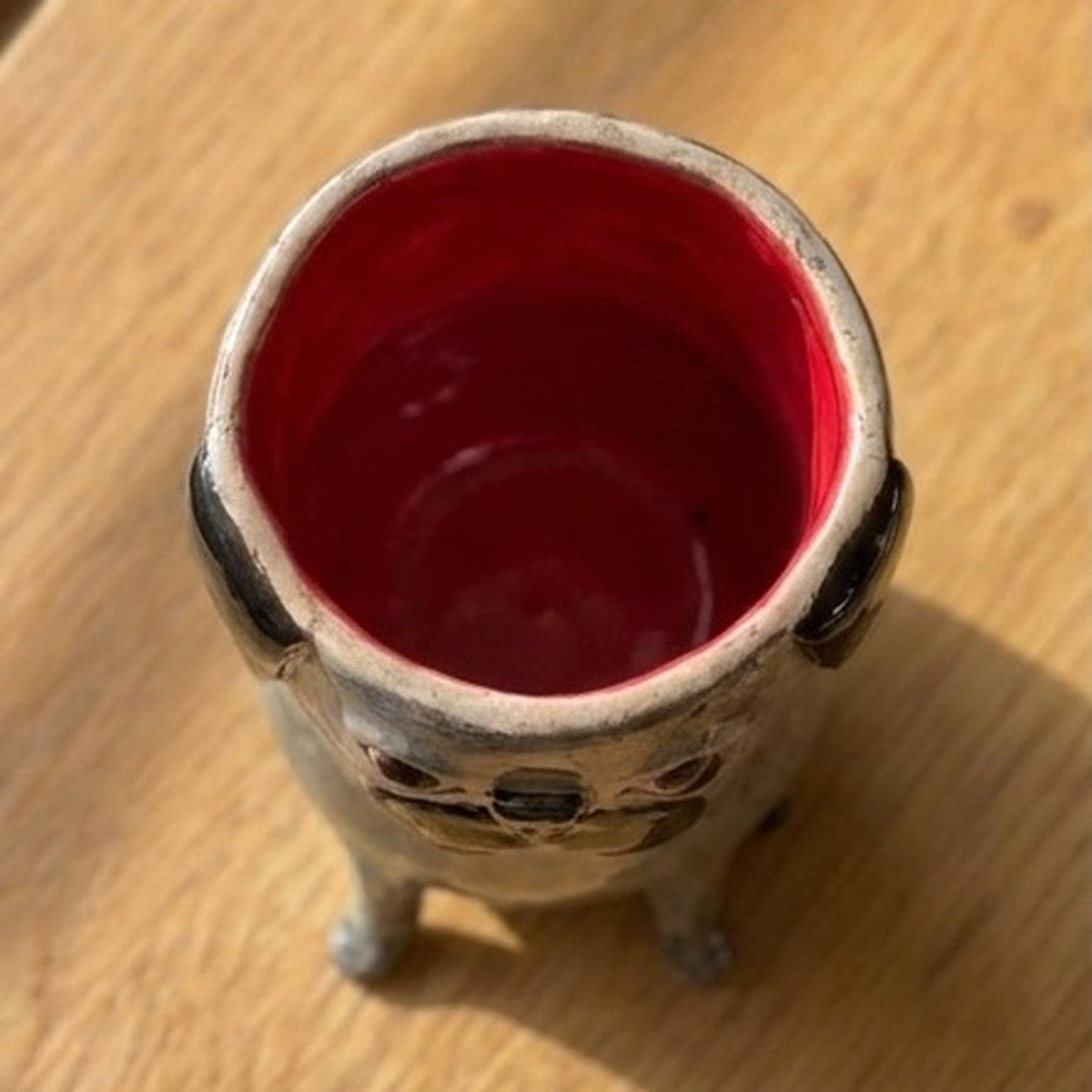 Archie the black pug ceramic vase, top-down view showing the red glazed interior