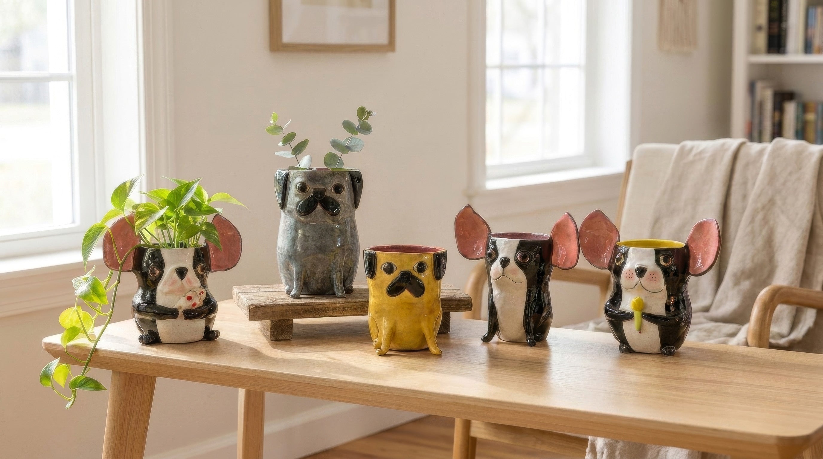 Colorful handmade ceramic dog planters with plants on a wooden table