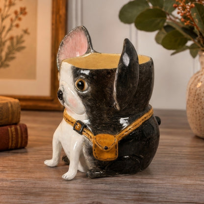 Fletcher, a handmade ceramic Boston Terrier vase, side view showing his sitting pose and tan satchel with a buckle strap