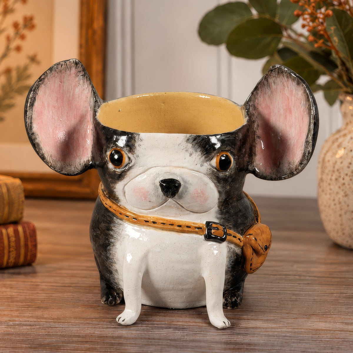 Fletcher, a handmade ceramic Boston Terrier vase with pink ears, wearing a little tan travel satchel across his chest