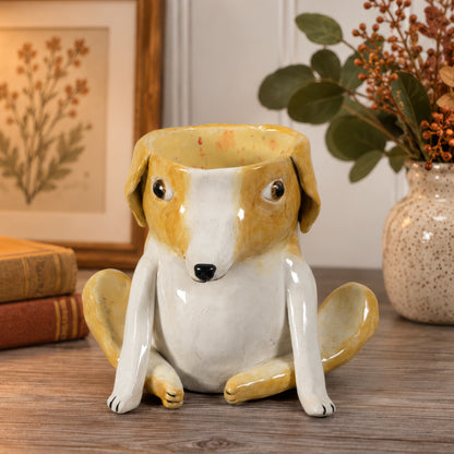 Vinnie, a handmade ceramic mixed breed dog vase in golden and white glaze, sitting with his legs stretched out